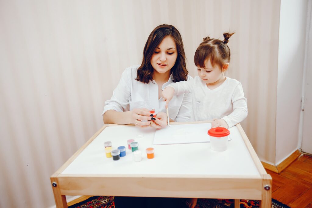 young mother along with her little daughter paints paper 1