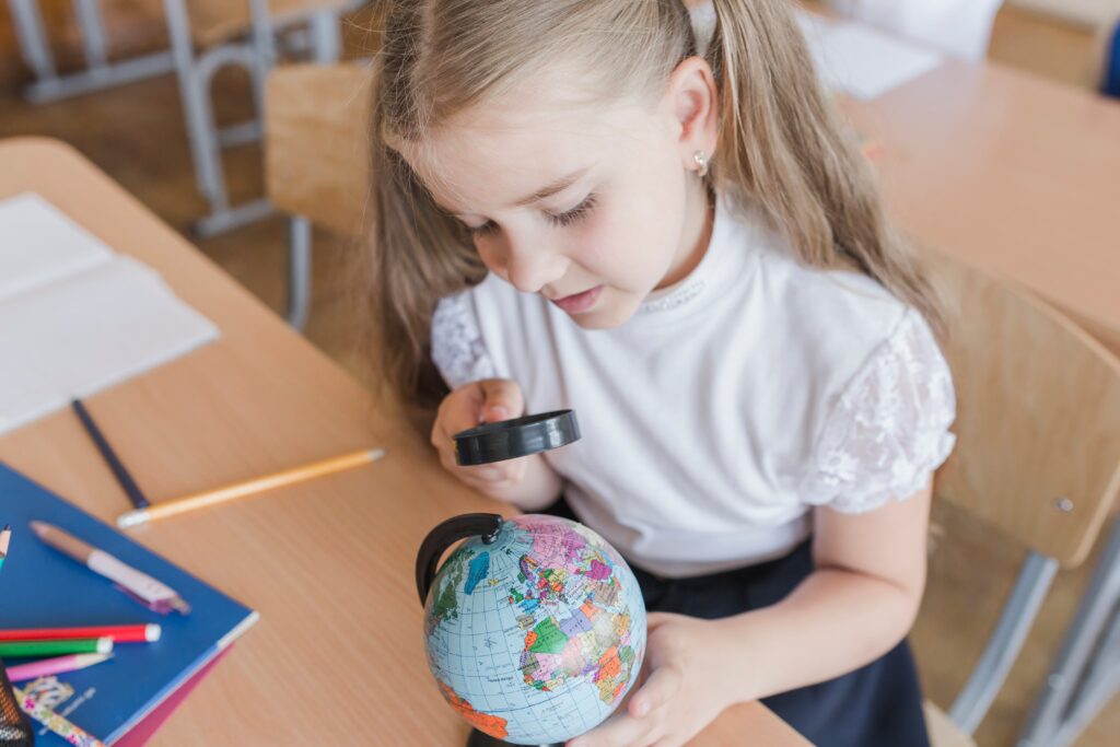 girl examining globe with magnifying glass 1