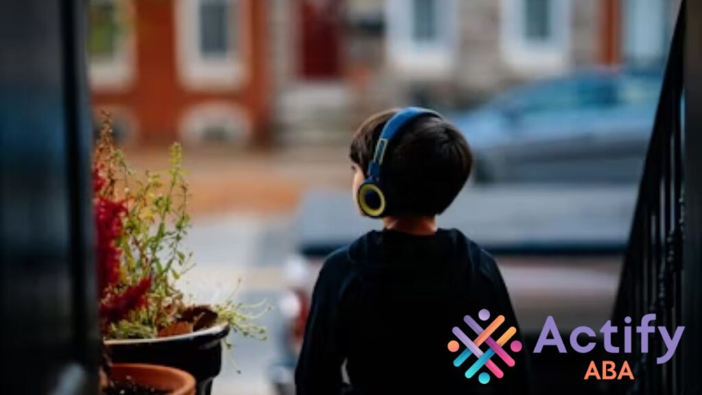 A young boy wearing headphones sits calmly outdoors with his back to the camera, against a dusky sky, symbolizing comfort and focus despite sound sensitivity in autism.