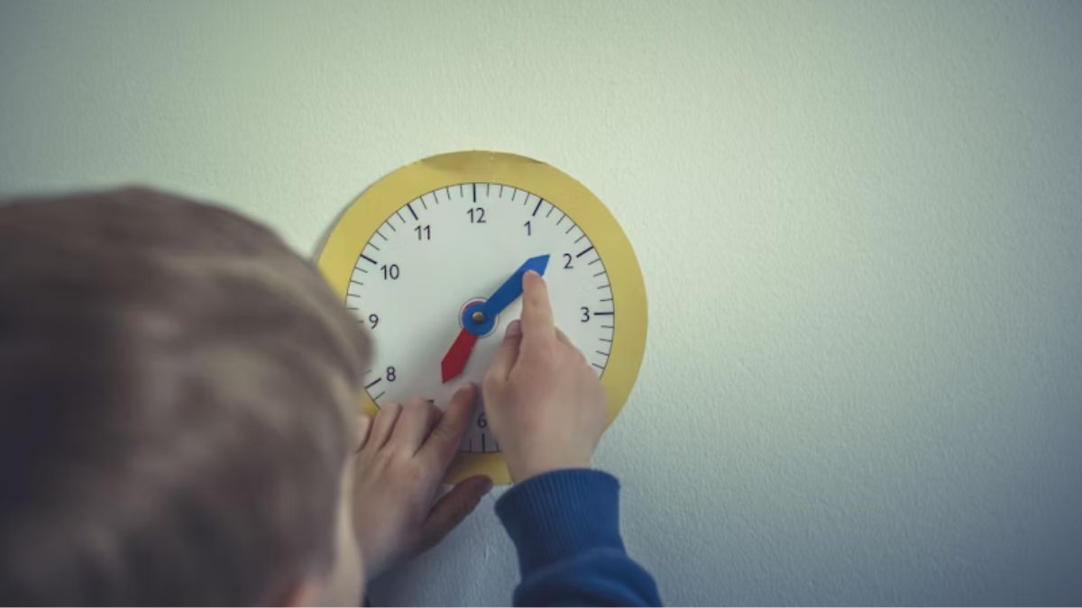 How many hours of ABA therapy is needed: A young boy, his back to the camera, winds a paper toy clock during a focused learning activity.