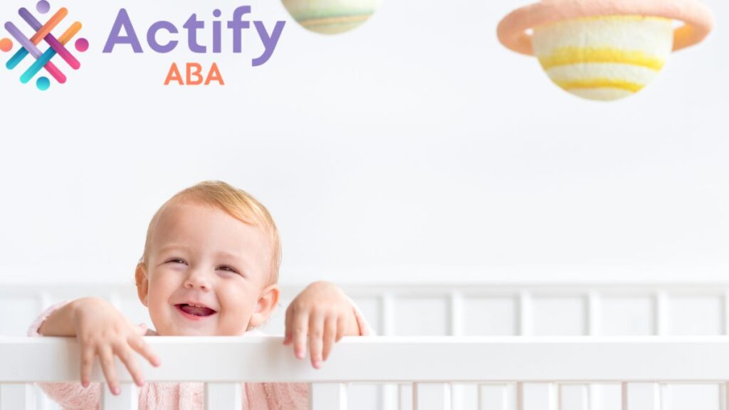 A smiling baby in a white room looks up from a crib, showing proprioception in autism.